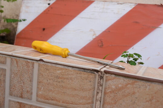 Chave Philips amarela no quintal em cima do piso, matérias de construção
