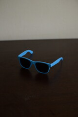 Óculos escuro azul em cima da mesa do quarto aberto