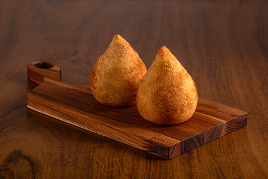 Typical Brazilian snack. Coxinha on wooden cutting board. Wooden background.