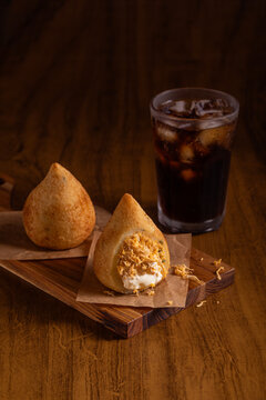 Typical Brazilian snack. Coxinha on wooden cutting board. Wooden background.