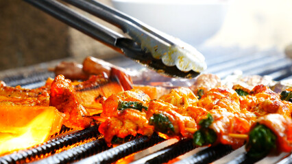 BBQ Barbecue grilled meat stick on fire flame with hot charcoal cooking outside. Beef grilling...