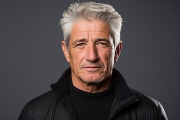 Portrait of a senior man with grey hair wearing a black jacket.