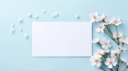 Naklejka na ściany i meble A blank white card surrounded by delicate white cherry blossoms on a soft blue background, perfect for a gentle spring message.