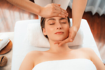 Caucasian woman enjoying relaxing anti-stress head massage and pampering facial beauty skin recreation leisure in dayspa modern light ambient at luxury resort or hotel spa salon. Quiescent