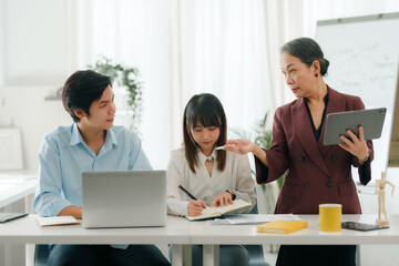 Asian boss or senior employee provide professional help and guidance to intern, practice corporate teamwork communication skill.