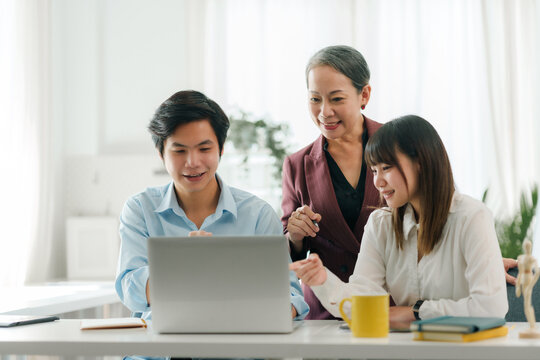 Asian boss or senior employee provide professional help and guidance to intern, practice corporate teamwork communication skill.