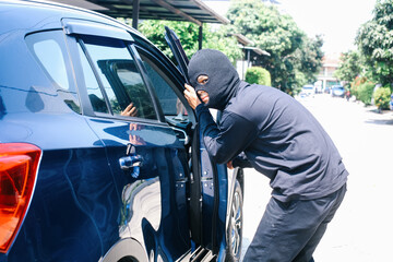 Obraz premium A criminal man with open the door and break into the car. Hijacker and car theft concept.