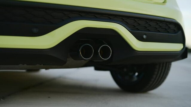 Close up of dual exhaust pipe on qualitative sports car. Back of bright yellow car with rear defuser. smooth curve in contempotary automobile design