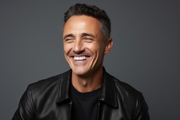 Portrait of a smiling middle-aged man in a black leather jacket, isolated on grey background