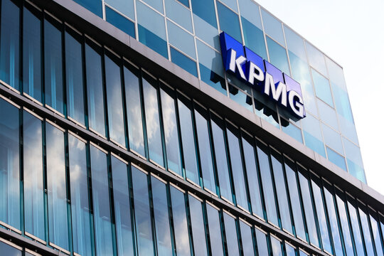 Building exterior and logo or brand or sign of KPMG Berlin. Suitable for design cover, wallpaper, background, report or publication. Clouds in blue sky background.