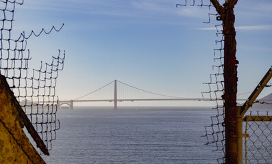 Golden gate bridge framed with a broken fence  - Powered by Adobe