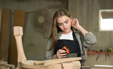 A female craftsman furniture designer makes a chair, marks various dimensions on a blueprint, and assembles a wooden one. Carpenter working in the studio
