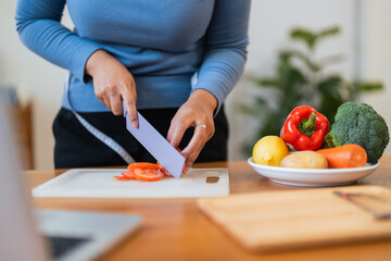 Obraz na płótnie Canvas Fat woman cook in kitchen and chopping fresh vegetable on chopping board. health care concept Eat healthy food to lose weight