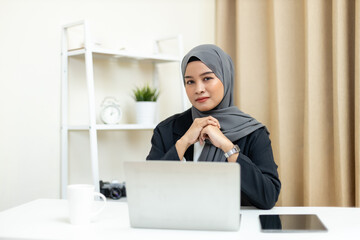 Young muslim beautiful businesswoman wear hijab working in modern business office use laptop computer. Islamic female manager looking at camera.