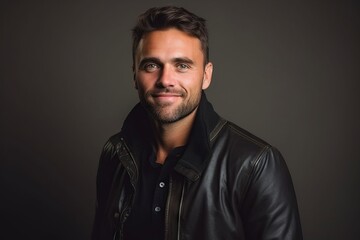 Portrait of a handsome young man in leather jacket on dark background
