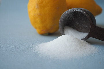 Coarse salt in a spoon and lemon on black background 
