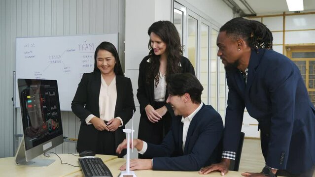 A diverse group of coworkers meeting around a desktop computer, actively discussing strategy and brainstorming ideas. Teamwork and cooperation are evident, promoting success and employee support.