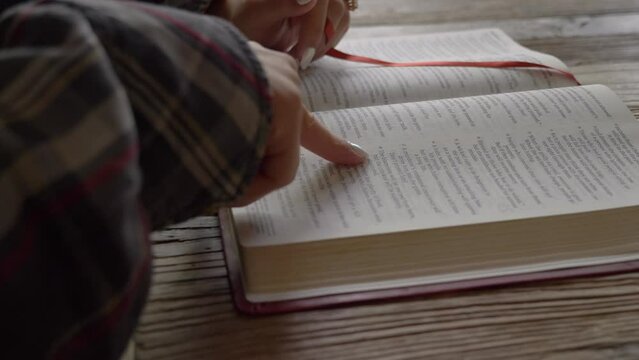 Close up female hands reading bible studying religious scripture at home desk