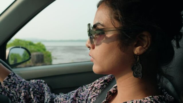 Young Woman with Sunglasses Paused at Red Traffic Light While Driving.
