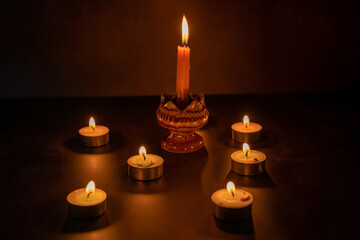 Many candles lit against a black background.Burning candles on dark tableMemory 