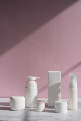 Skin care and beauty product packaging on pink background. Cosmetic bottle mockup under the rays of sunlight for beauty concept.