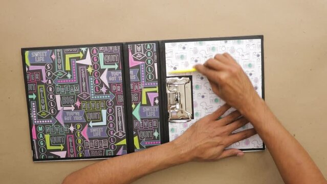 Using bone folder to smooth the inner cover of ring binder scrapbook