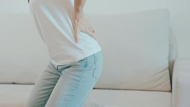 woman having back body ache during sitting on Couch at home. adult female with muscle pain due to Piriformis Syndrome, Low Back Pain and Spinal Compression. Office syndrome and medical concept
