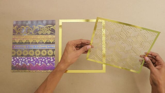 Decorated ornate paper and gold foil page frames laid on desk.