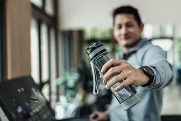 A man hold water bottle on treadmill in gym. Fitness, gym, workout and lifestyle concept.