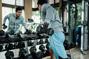 Fototapeta premium A man doing exercises triceps muscle with dumbbell in gym. Fitness, workout and traning concept.