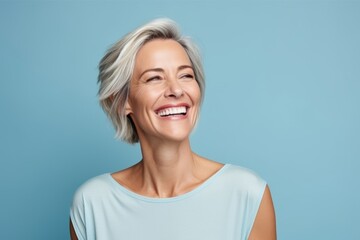 portrait of happy middle aged woman with grey hair on blue background