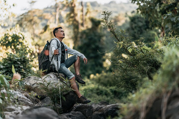 Naklejka premium Hikers sitting on rocks for rest in the stream flowing from the waterfall in the forest.
