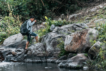 Hikers walk on rocks with dog in the stream flowing from the waterfall bact to his tent in hill.