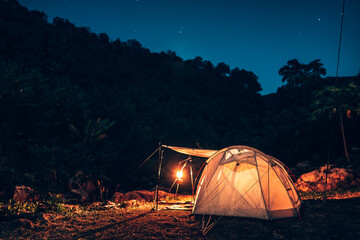 tents pitched on hillsides beside streams of water from waterfalls at night under star in the sky.