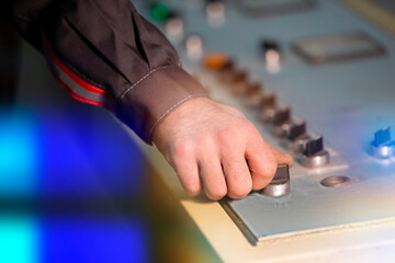 A worker's hand turns the starting switch to start production.