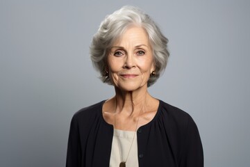 Portrait of a beautiful senior woman with grey hair on grey background