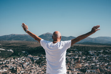 Back view of senior Caucasian man in Andalusia, Spain, looking at the landscape with outstretched...