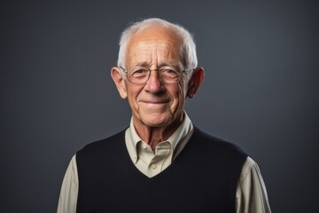 Portrait of a senior man with glasses on a dark background.