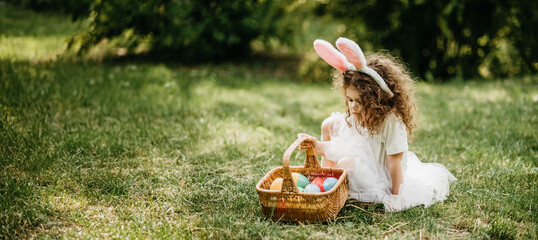 Easter egg hunt. Girl child Wearing Bunny Ears Running To Pick Up Egg In Garden. Easter tradition....