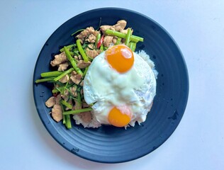 Stir fried morning glory with chicken and fried eggs on top of rice 
