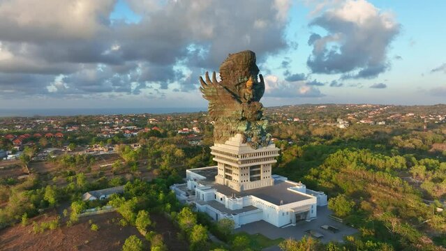 Drone video.Statue of Hindu god Garuda Vishnu Kenkhana With blue sky and clouds and sunlight in the morning located in Garuda Vesnu Kenjana Cultural Park, Bali, Indonesia.