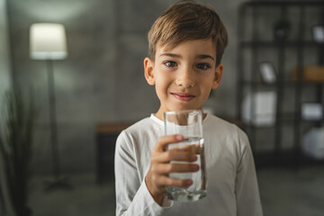 One boy caucasian kid stand at home hold glass of water thirsty drink - Powered by Adobe