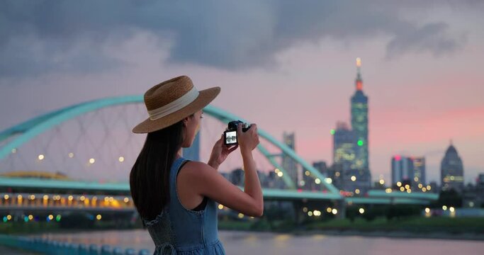 Woman use of digital camera to take photo in Taipei city in the evening