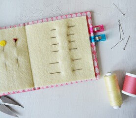 Simple handmade needle book, pins, thread spools and clips on white