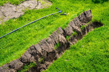 Self-installation of irrigation with a retractable sprinkler in the finished lawn. Laying water pipes with sprayers under the lawn for irrigation.
