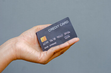 Closeup female hand holding a black credit card mockup with security chip embedded on a gray background