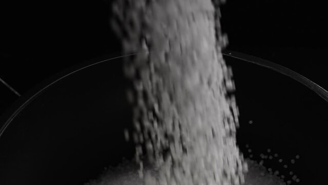 Filling the tank with plastic granules. The process of producing parts from polyethylene compound. White granules are poured into a container.
