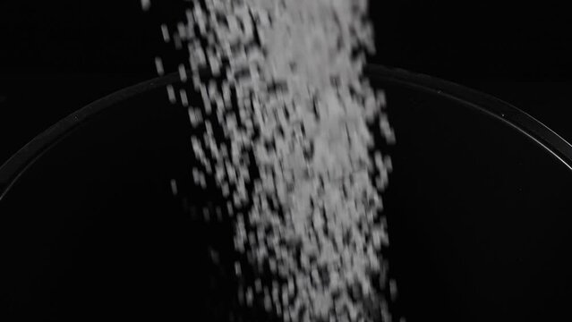 Filling the tank with plastic granules. The process of producing parts from polyethylene compound. White granules are poured into a container.