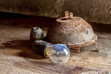 Old rusty lighting fixtures. A burnt-out light bulb. Electric lighting fixtures on a rough wooden...