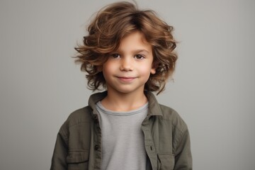 Portrait of a cute little boy with long curly hair. Isolated on grey background.
